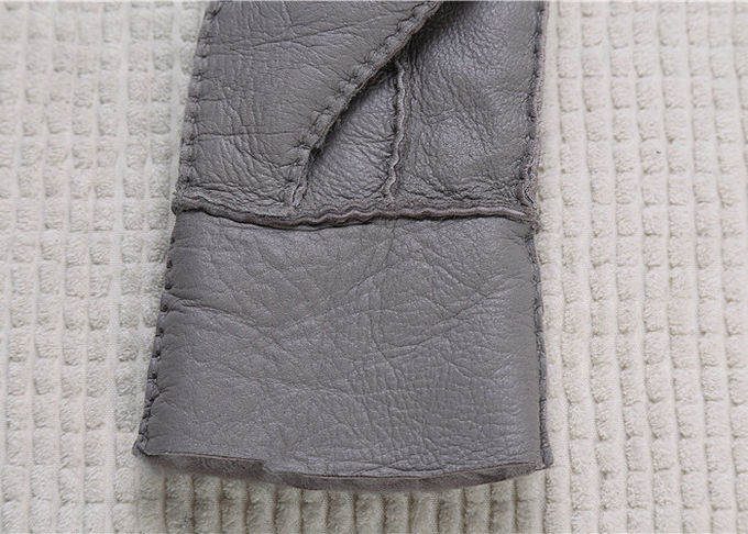 I guanti grigi della pelle di pecora i più caldi allineati pelliccia reale lisciano la superficie con il dito